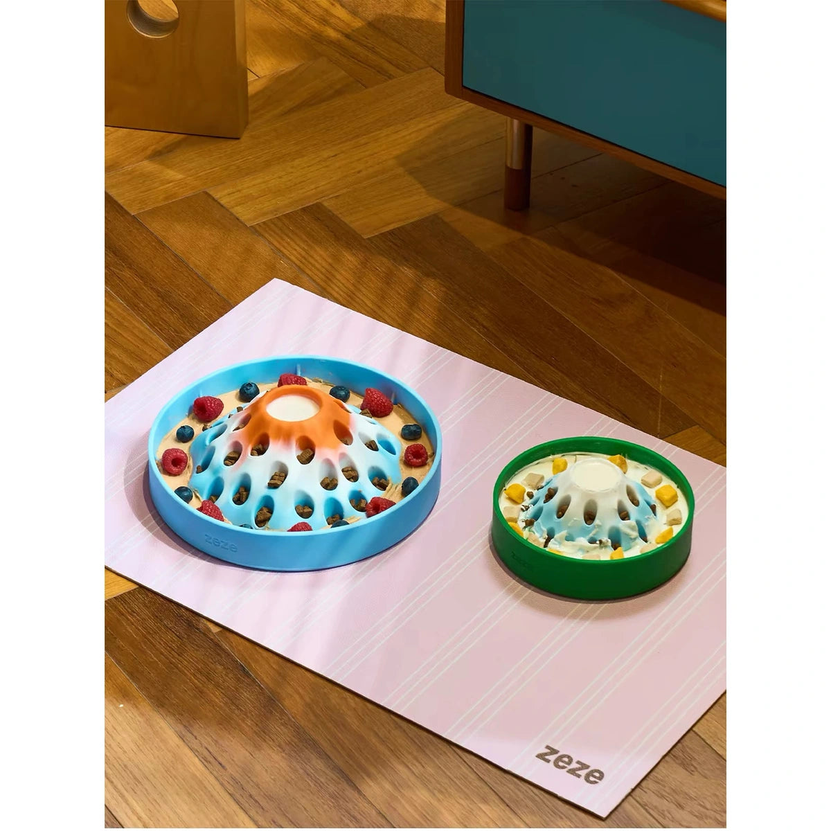 Two ZEZE feeding bowls on a floor mat