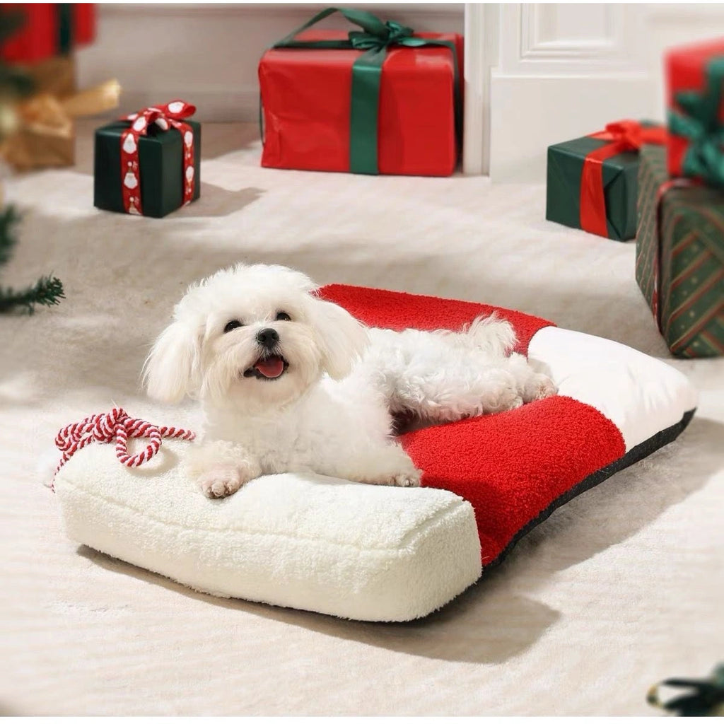 Small dog resting on the red and white Christmas pet bed