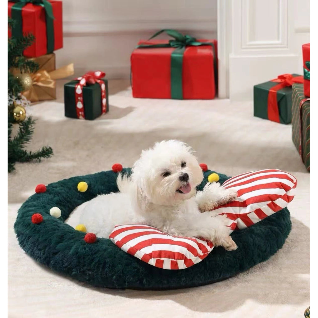Small dog in the round green bed beside Christmas decorations