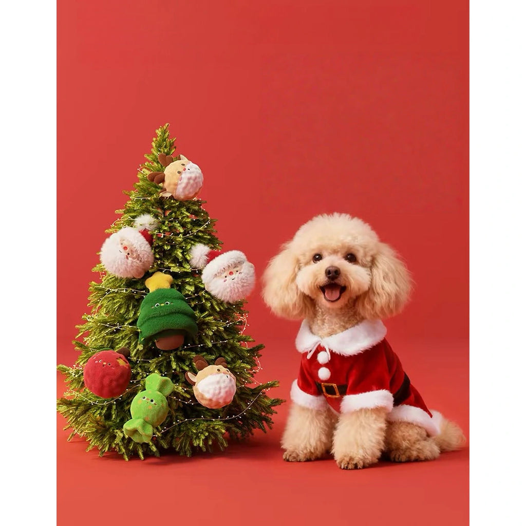 Dog sitting beside a Christmas tree and plush toy