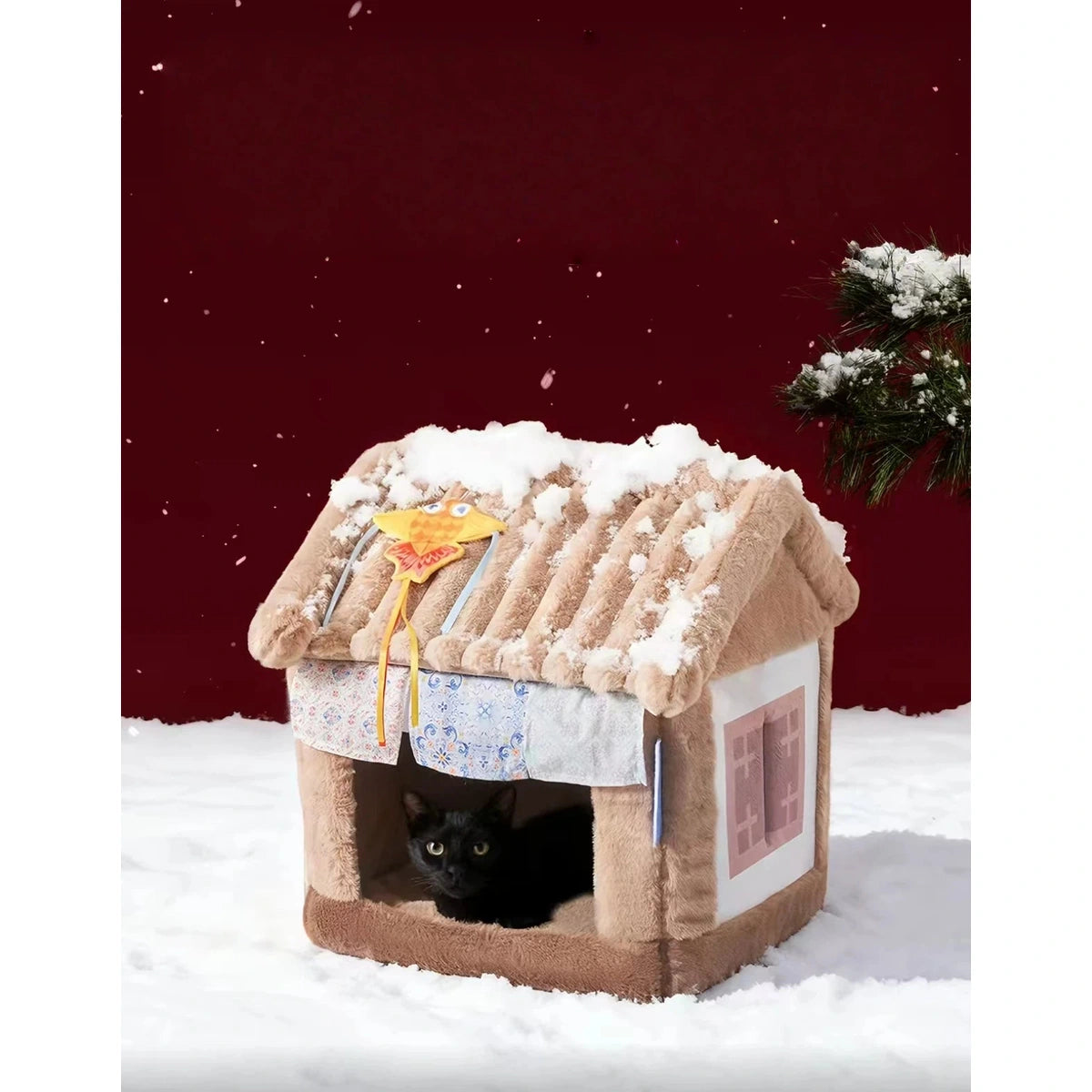 Black cat resting inside the Petstar beige house in a snow-themed product scene