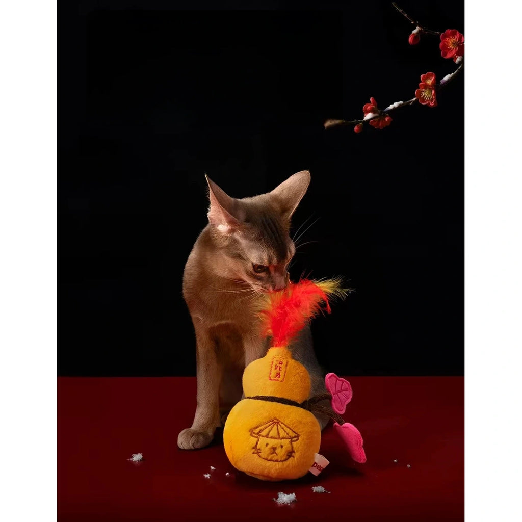 Cat playing with the yellow gourd-shaped plush toy